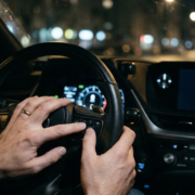 Kierowca wpisujący kod PIN na przyciskach kierownicy w aucie premium, podczas gdy na ekranie nawigacji wyświetla się brak sygnału GPS spowodowany zagłuszarką. Skuteczne zabezpieczenie przed kradzieżą w autosecurity.pl.